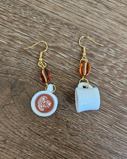Pair of earrings with coffee-themed charms on a wooden surface